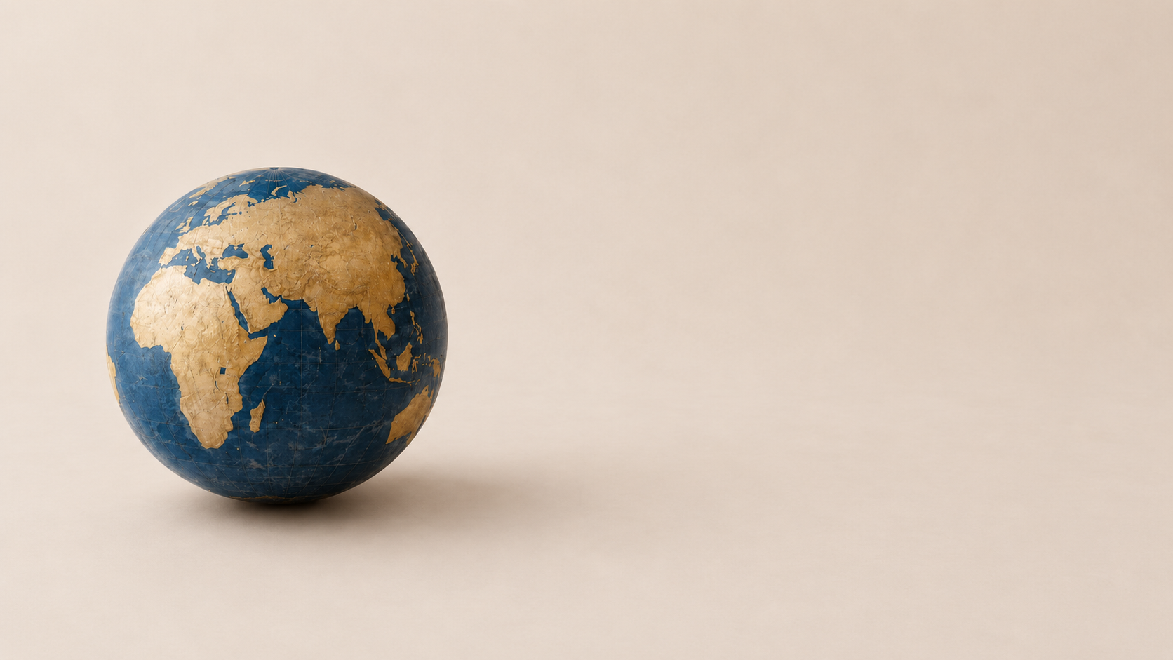 A weathered globe resting on a warm sandstone surface.